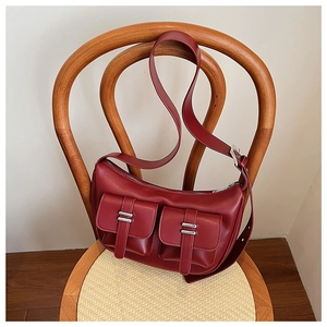 Detail of burgundy leather half-moon bag with cargo pockets hanging on a vintage wooden chair