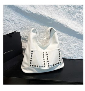 Close-up of white leather tote bag featuring front pockets and silver rivet details