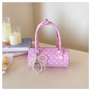 Vue détaillée du sac cylindrique rose à pois avec pendentif noeud perle et coeur argenté
