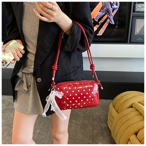 Détail du sac rouge à pois avec un nœud en tulle délicat et breloques en perles
