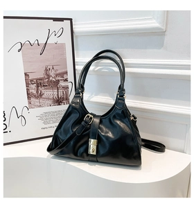Détail du sac sous le bras en similicuir noir avec finition brillante et boucle dorée