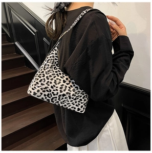 Detail of glossy black and white leopard print shoulder bag with gold metal buckle