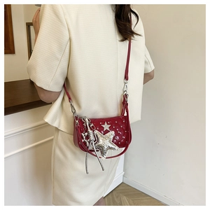 Detail of red patent leather crossbody bag with silver star charm and studs in Y2K style