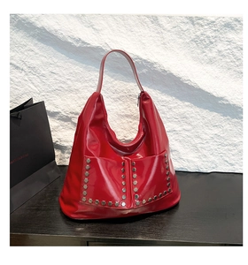 Close-up of shiny red patent leather hobo bag featuring silver hexagonal metal rivets