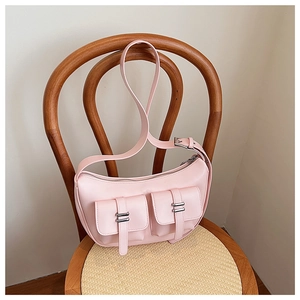 Detail of pink faux leather half-moon bag with cargo pockets on a wooden chair