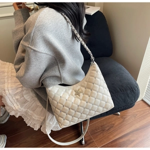 Détail du sac matelassé blanc avec strass et logo étoile dorée porté par un mannequin