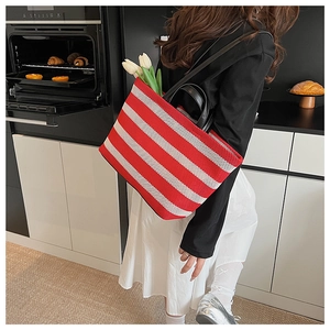 Photo de style d'un cabas rayé rouge et blanc avec des poignées en cuir noir