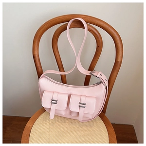 Detail of light pink crescent bag with silver buckles on a wooden chair background