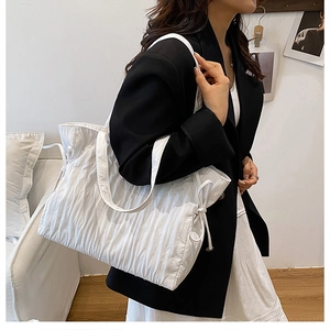 Dettaglio della borsa tote a pieghe bianca con coulisse laterale e trama in nylon goffrato