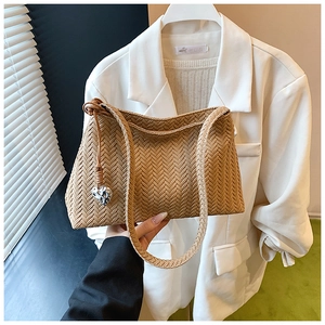 Detail of caramel brown woven bag texture with a silver heart-shaped pendant