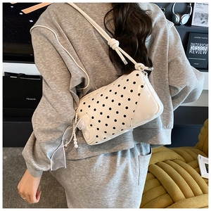 Détail du sac à main à pois en cuir crème avec nœud en mousseline et breloque en perle