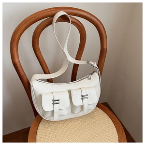 Detail shot of a white faux leather moon bag with utility pockets and silver metal buckles