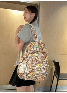 Detail of 3D knitted bears and daisies on a beige backpack with cute plush charm