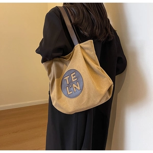 Side view of khaki canvas tote bag with leather handles shown on a black wool coat