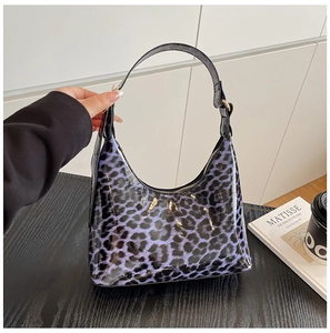 Detail of glossy purple leopard print shoulder bag with adjustable black strap and hobo shape