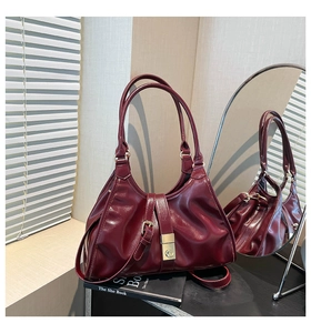 Détail du sac à main bordeaux en cuir verni avec boucle dorée et sangles décoratives