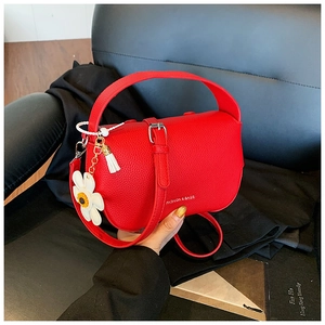 Close-up of red litchi texture handbag with daisy charm and tassel detail