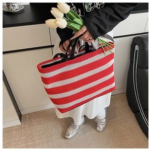 Détail d'un sac cabas en maille à rayures rouges et blanches avec anses noires