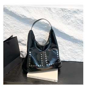 Detailed view of black hobo bag with silver hexagonal rivets and two front pockets