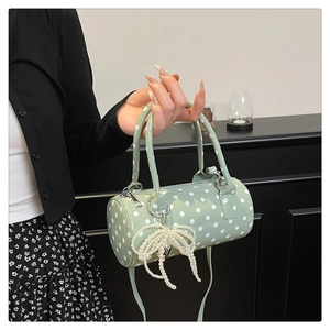 Vue détaillée d'un sac cylindrique à pois vert menthe avec nœud en perles et bandoulière