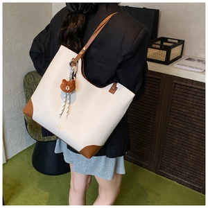 Detailed back view of a white lychee leather tote bag with brown contrast straps on model
