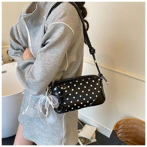 Sac à pois avec nœud en tulle et pendentif perle, porté par un mannequin en intérieur