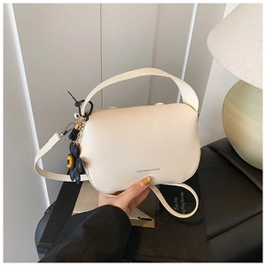 Detailed view of cream lychee texture leather with Fashion & Bags text and daisy charm