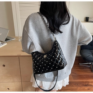Détail d'un sac bandoulière matelassé noir avec strass argentés et emblème étoile en métal