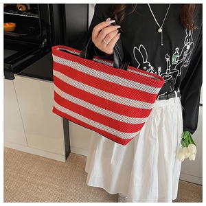Détail du sac cabas tissé à rayures rouges et blanches avec anses en cuir noir