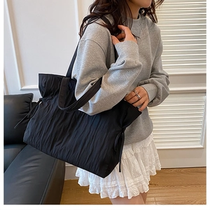 Dettaglio della borsa tote trapuntata nera oversize con coulisse su modella fashion