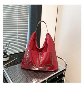 Close-up of red patent leather hobo bag with hexagonal metallic rivets on industrial cart