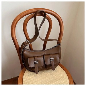 Detail of dark brown leather crescent bag with double front flap pockets and silver hardware