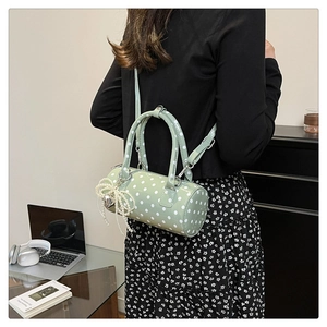 Sac à main cylindrique vert à pois avec breloque nœud perlé porté par modèle
