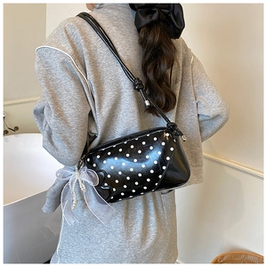 Détail du sac à pois avec un nœud en organza et un pendentif en perles blanches