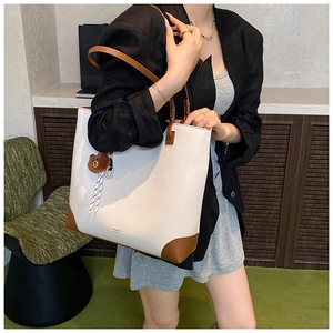 Detail of off-white lychee grain leather tote bag featuring brown contrast handles and trim