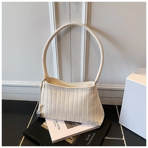 Detailed view of cream woven bucket bag texture with silver leopard charm on black desk