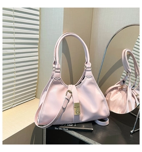 Détail d'un sac à main rose clair avec boucle dorée sur un plateau en bois noir