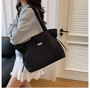 Dettaglio della borsa tote nera a pieghe con texture a coulisse e etichetta bianca