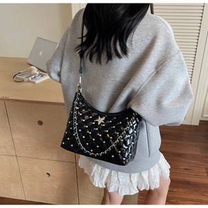 Détail du sac matelassé noir avec strass et pendentif étoile porté à l'épaule