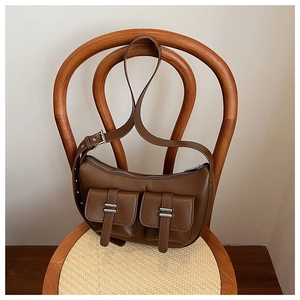 Detail view of brown semi-circle shoulder bag with dual metal buckle pockets