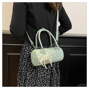 Vue détaillée du sac cylindrique vert clair à pois avec nœud en perles et pendentif cœur