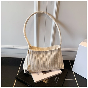 Detail of cream woven shoulder bag featuring a heart pendant and herringbone texture