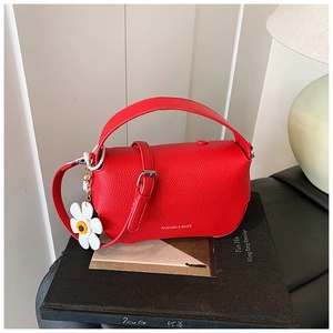 Detail of red lychee texture handbag with sunflower charm on photography book