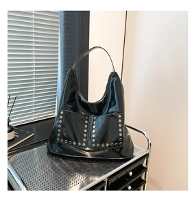 Detail shot of black patent leather hobo bag with silver hex rivets and front pockets