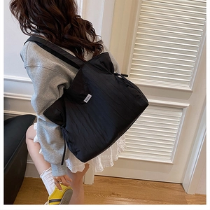 Dettaglio borsa tote nera trapuntata con texture verticali e coulisse laterale