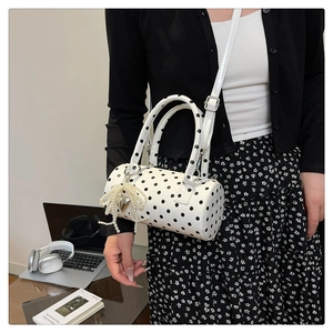 Sac cylindrique à pois avec breloque cœur en perles porté dans un cadre de bureau