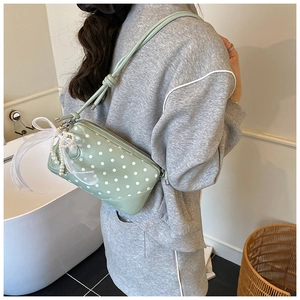Détail du sac à main vert menthe à pois avec nœud en dentelle et chaîne perlée
