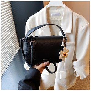 Detailed shot of black lychee grain leather crossbody bag with sunflower charm accessory
