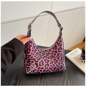 Detail of pink leopard print underarm bag with black shoulder strap and gold hardware