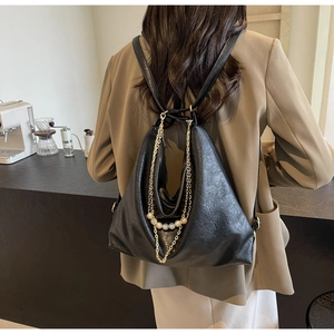Rear view of a black faux leather hobo backpack with gold chains and pearl pendant